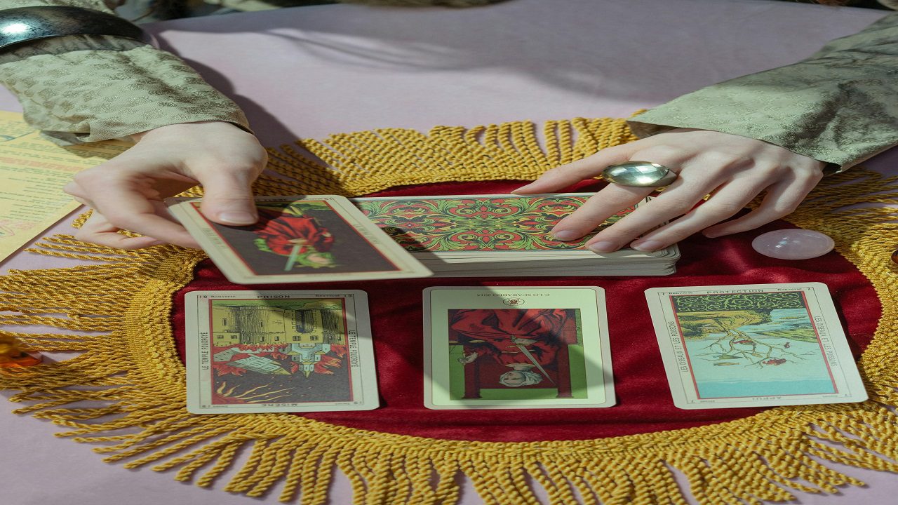 A woman holding a tarot card, examining it closely with a focused expression on her face.